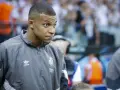 Kylian Mbappé w szarej kurtce z logo Realu Madryt, gotowy do gry.