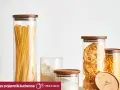Szklane pojemniki z drewnianymi pokrywkami prezentują makaron świeży z lodówki kontra suchy z paczki: tagliatelle, fusilli i długie wstążki.