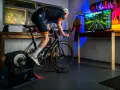 Cyclist on a Tacx trainer, connected to a TV displaying a Zwift course. This setup showcases Zwift compatible devices for an immersive indoor cycling experience.