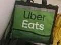Zielona torba Uber Eats, obok żółtej torby Glovo. Taki widok może oznaczać potencjalne uber eats zarobki.