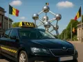 Schwarzer Taxi in Belgien vor dem Atomium. Belgische Flaggen wehen im Hintergrund.