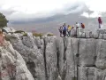 Grupa turystów na skalnym szczycie, podziwiająca widok na góry. Może to być okolica stolicy Czarnogóry, Podgoricy.