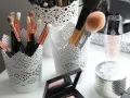 Des pinceaux de maquillage et des produits de beauté dans des pots ajourés. Une belle organisation pour le recyclage du maquillage.