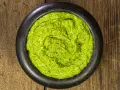 Pesto genovese ricetta originale in un mortaio di pietra, su un tavolo di legno rustico. Fresco e profumato.