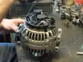 Warsztat samochodowy. Mechanik pracuje nad regeneracją alternatora. Sprawdź, jaka jest regeneracja alternatora cena.