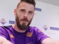 David de Gea, con barba y camiseta morada, posa ante un fondo con logos.