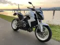 Biały motocykl Honda z silnikiem 35 kw nad rzeką o zachodzie słońca.