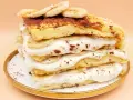 Wysoki omlet z bananem, przełożony kremem i plasterkami banana, posypany kakao. Pyszny deser na talerzyku.