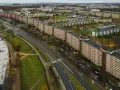 Widok z lotu ptaka na najdłuższy blok w Europie, rozciągający się wzdłuż ruchliwej drogi i otoczony zielenią oraz innymi budynkami mieszkalnymi.