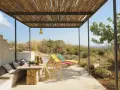 Porches sencillos y bonitos con mesa de piedra, asientos cómodos y tumbonas bajo un techo de madera.