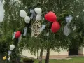 Drewniany napis "Witamy Parę Młodą" na gałęziach iglaków, ozdobionej białymi i czerwonymi balonami. Idealne śmieszne teksty na bramy weselne!