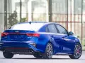 Niebieski sedan Kia Forte z widokiem z tyłu, z czerwonymi akcentami i sportowymi felgami.