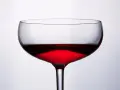 Cachaca co to? Kieliszek z czerwonym, przejrzystym płynem, który może być cachacą, na jasnym tle.