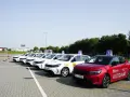 Rząd białych i czerwony samochód nauki jazdy z literą "L" na dachu. Zastanawiasz się nad koszt egzaminu na prawo jazdy?