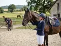 Une cavalière souriante, casque sur la tête, tient son cheval. La **FEI definition** de l'équitation est ici incarnée par cette scène paisible.