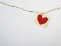 A red heart on a small fabric square, hung by a clothespin on a string. A simple symbol, asking: does God love everyone?