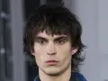Joven con un corte de pelo mullet desordenado, mirada intensa y cejas marcadas.