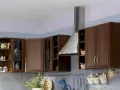 Jasne ściany w kuchni z brązowymi meblami tworzą przytulną atmosferę. Delikatny fiolet i błękit na ścianach dodają elegancji.
