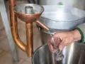 Ein Schnaps wird in ein Glas destilliert. Die Kupferapparatur zeigt, wie man Schnaps brennt.