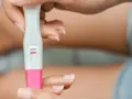 Dłoń trzyma test ciążowy z jedną czerwoną kreską. Kiedy zrobić test ciążowy? Najlepiej po terminie spodziewanej miesiączki.