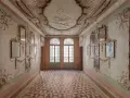Corridoio decorato con stucchi dorati e specchi, soffitto affrescato e pavimento a rombi. Un assaggio dell'eleganza del Casino Venier.