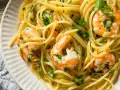 Un piatto invitante di pasta con gamberetti, condita con prezzemolo fresco e un filo d'olio.