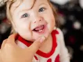 Ein lächelndes Baby mit blauen Augen zeigt stolz seine ersten Zähnchen. Das Baby zahnen ist ein aufregender Meilenstein!