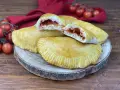 Panzerotti al forno dorati e ripieni di pomodoro e mozzarella filante, pronti per essere gustati.