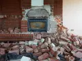Démolition d'une cheminée en briques, laissant le conduit apparent. Des débris de briques jonchent le sol.
