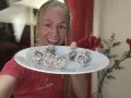 Glad kvinna visar upp en tallrik med hemgjorda chokladbollar, perfekta för ett snabbt och enkelt chokladbollar recept.