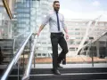 Uomo con pantaloni neri come abbinarli: camicia azzurra e cravatta blu, un look da ufficio moderno.
