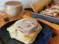 Pyszne cynamonki przepis na talerzu, obok kubek kawy i blaszka z innymi słodkościami. Idealne na jesienne popołudnie.