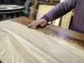 Mano che applica la finitura a cera dopo impregnante su un tavolo di legno grezzo, esaltandone le venature.