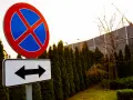 Znak zakaz parkowania z tabliczką wskazującą kierunki.