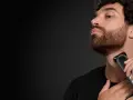Hombre con barba cola de pato, perfil, usando una recortadora Braun para definir su estilo.