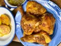 Pollo dorado y jugoso troceado en un plato azul, acompañado de patatas y pimientos.