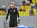 Mateusz Zych, bramkarz w czarnej koszulce z numerem 77, gotowy do akcji na boisku.