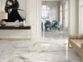 Elegancka łazienka z marmurowymi płytkami, które zachwycają klasą ścieralności. Wnętrze zdobią błękitne krzesła i złote detale.
