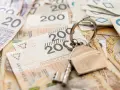 Klucze do domu na stosie polskich banknotów. Może to symbolizuje spłatę kredytu hipotecznego lub inwestycję, a może nawet windykację Santander.