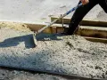 Pracownik rozprowadza świeży beton B25. Czas wiązania betonu zależy od wielu czynników.