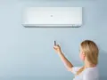 Donna con telecomando regola il condizionatore Haier. Il suo significato è il comfort climatico.