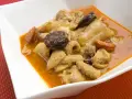 Un plato de callos a la madrileña con chorizo y morcilla en una cazuela blanca.