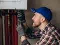 Tecnico con guanti controlla la caldaia a condensazione, forse per un insolito rumore.