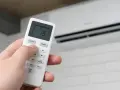 Mano ajustando el control remoto del aire acondicionado por la noche a 18 grados.