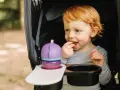 Rotschopf-Kind im Kinderwagen, isst genüsslich einen Snack. Dieses Kind hat immer Hunger und freut sich über jede Leckerei.