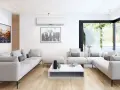 Salón moderno con sofás blancos, mesa de centro y aire acondicionado para la renovación de aire. Ventanal con vistas al jardín.