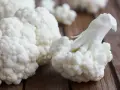 Białe różyczki kalafiora na drewnianym tle.