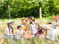 Familie genießt einen sonnigen **Picnic Berlin** im Grünen mit Hund.