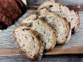 Ein Laib Sauerteigbrot, angeschnitten, mit sichtbarer, knuspriger Kruste. Die Scheiben zeigen eine luftige Krume. Hoffentlich ist die brotkruste zu hart, um sie zu genießen.