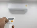 Mano che preme il telecomando per regolare il condizionatore. Il suo significato è comfort e controllo della temperatura.
